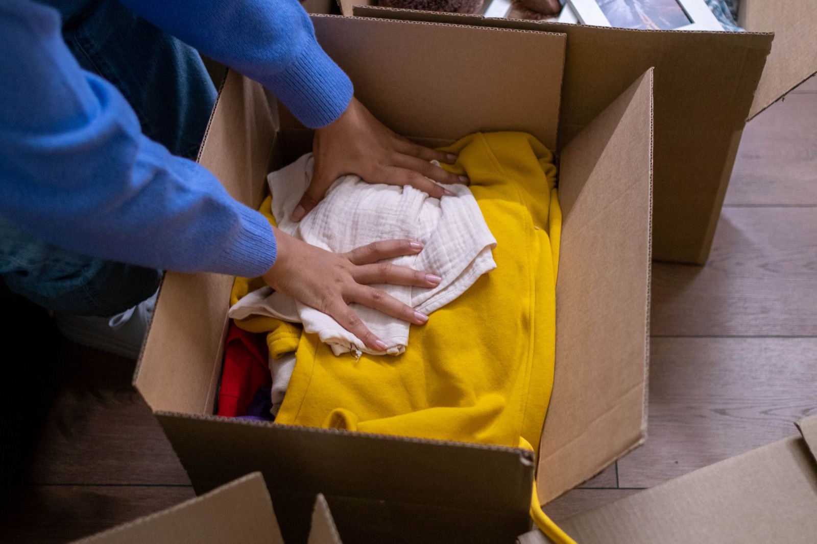 Người ngồi giữa nhà đóng gói quần áo vào thùng carton